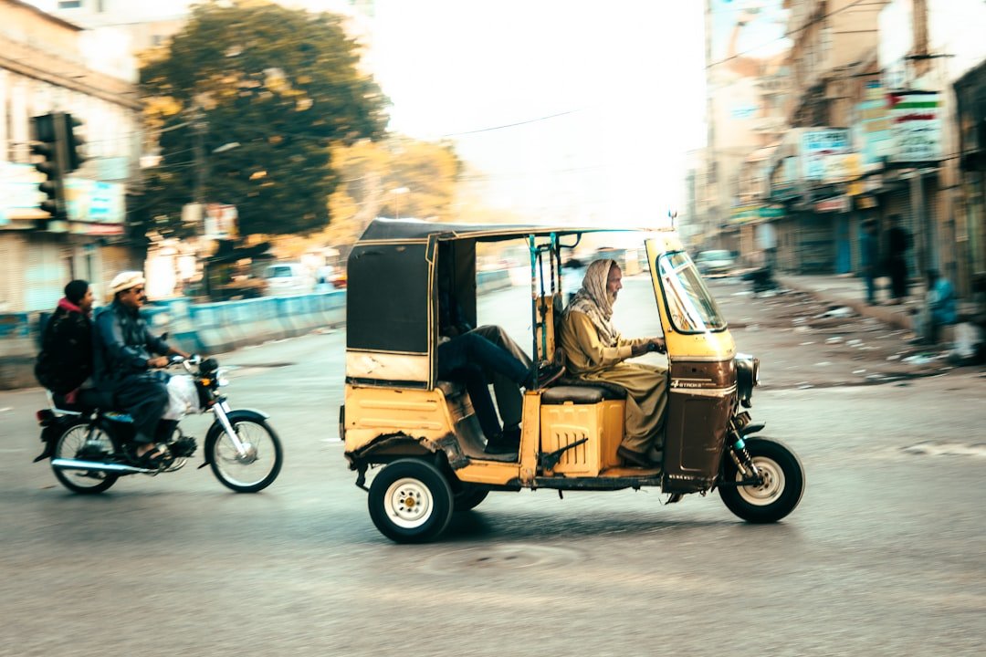 Driver on motorcycle beside a car on a KPK road, representing DLIMS KPK driving license verification